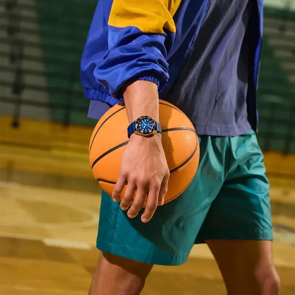 Citizen Eco-Drive BN0267-04L med blå urtavla och blått armband på handleden hos en man som håller en basketboll